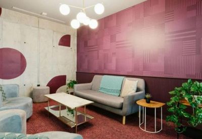 Cosy meeting lounge with a pink textured feature wall and grey velvet seating.