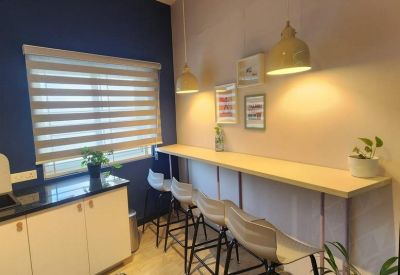 Cafe-style breakout area with a long wooden counter, bar stools, and hanging pendant lights.