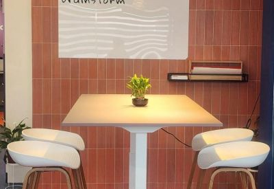 Brainstorming area with a high table, white bar stools, and a terracotta tile wall.