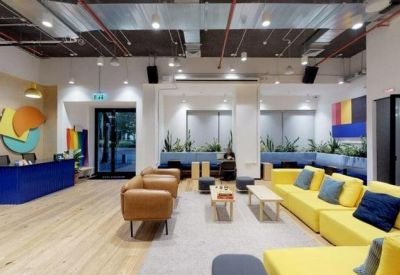 Lobby area featuring a bold blue front desk, tan armchairs, and a vibrant yellow sofa.