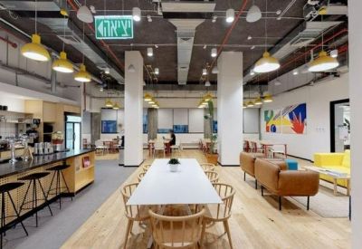 Long white communal dining table adjacent to a modern kitchen and bar area.