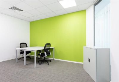 Compact two-person meeting room with a lime green accent wall and white storage cabinet.