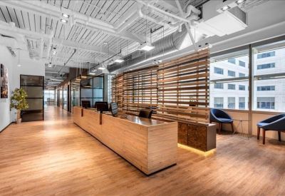 Minimalist reception area featuring a light wood front desk and industrial white ceiling details.