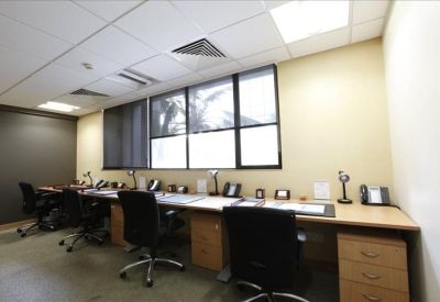 Workspace with a long desk against a window and ergonomic chairs.