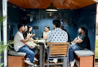 Group of people having a meeting inside a unique wooden house-shaped booth.