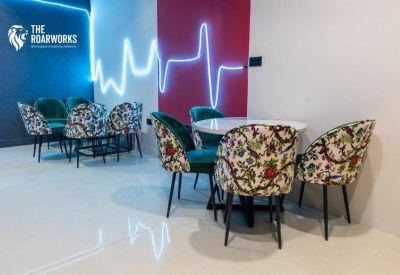 Vibrant breakout area with colourful patterned chairs and neon wall lighting.