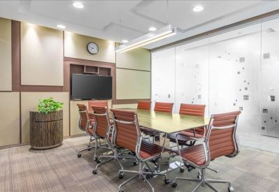 Professional meeting room with a large table, orange chairs, and a flat-screen television.