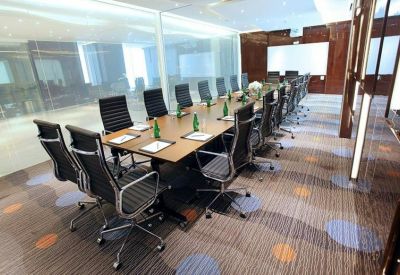 Spacious boardroom featuring a long wooden table, ergonomic chairs, and glass partitions.
