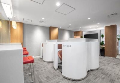 Contemporary breakout space with curved white privacy booths and red bar stools.