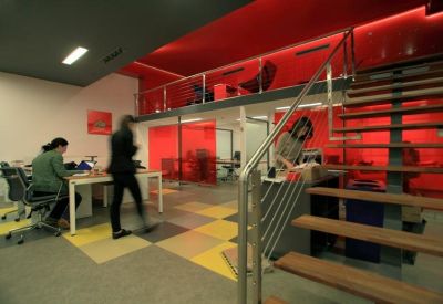 Modern bi-level workspace featuring vibrant red accent walls, a mezzanine level, and a modular checkered floor.