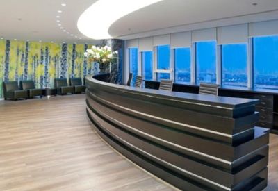 Spacious reception area with a long curved desk, wood floors, and a vibrant feature wall.