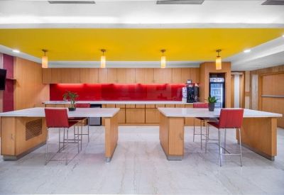Modern breakout area with a yellow ceiling, red backsplash, and high stools.