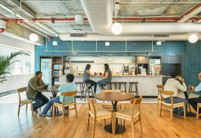Bright communal kitchen and cafe area with bar seating and wooden floors.
