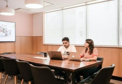 Professional meeting room with a large wooden table and integrated presentation screen.