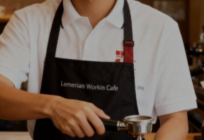 Barista preparing coffee behind a modern wooden service counter.