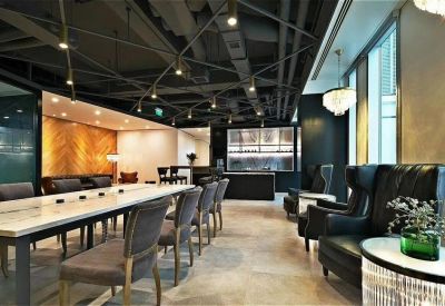Spacious communal lounge and coworking area with industrial ceilings and plush leather seating.