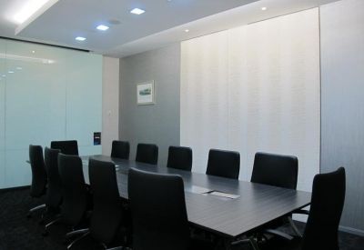 Modern boardroom with a long dark table and sleek black leather chairs.