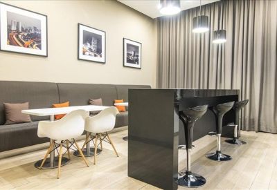 Communal breakout area with a sleek black breakfast bar, white café chairs, and wall art.