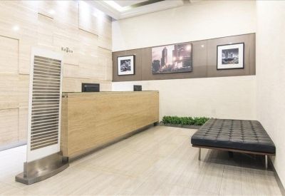 Modern reception area with a light wood front desk and minimalist black bench.