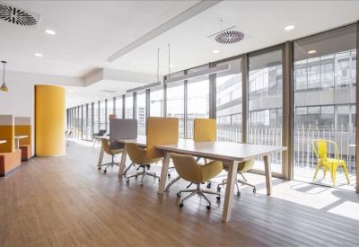 Bright coworking area with yellow chairs and large windows.