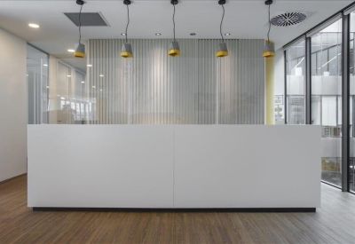 Minimalist white reception desk with modern pendant lighting.