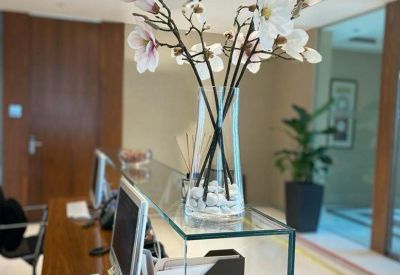 Reception desk with modern glass partition and white magnolia flowers in a vase.