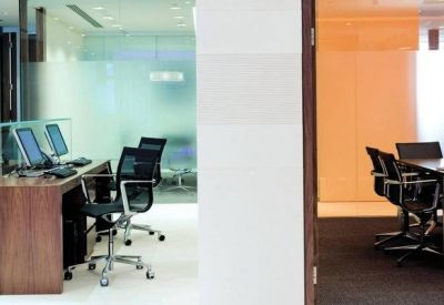 Private office space featuring a wooden desk and glass partitions looking into a hallway.