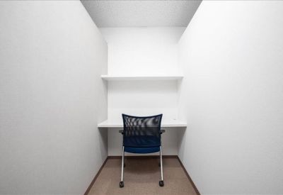Minimalist private study booth with a white desk and navy mesh chair.