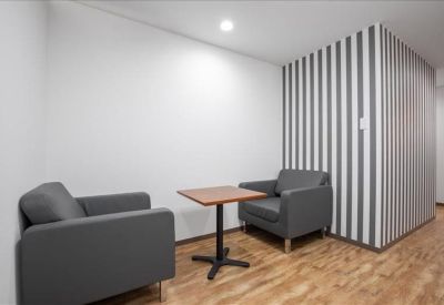 Meeting nook with two grey armchairs and a feature striped wall.