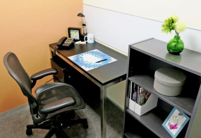 Compact private office suite featuring a dark wood desk, ergonomic chair, and a grey bookshelf.