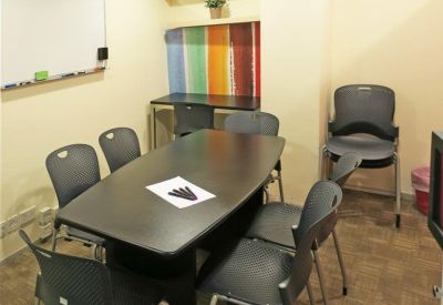 Professional meeting room with a dark oval table, black chairs, and a colorful striped accent wall.