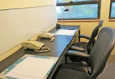Two-person office setup with side-by-side desks, landline phones, and a large whiteboard.