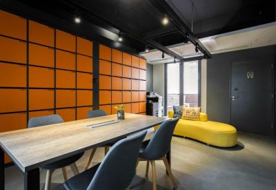 Vibrant breakout space featuring an orange grid wall and a curved yellow sofa.