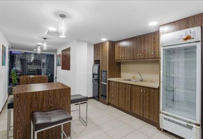 Communal kitchen and dining area featuring wood cabinetry, breakfast bar, and tall stools.
