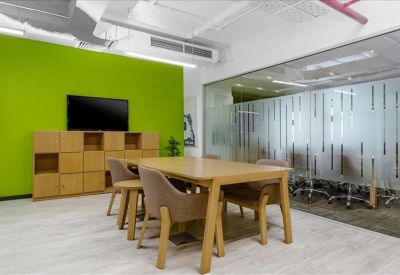 Modern meeting area featuring a light wood table, lime green wall, and glass partitions.
