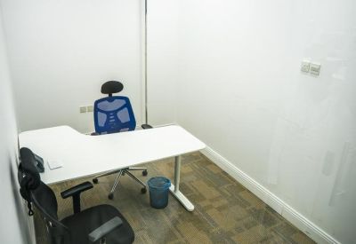 Small workstation in a white room with a L-shaped desk and blue chair.