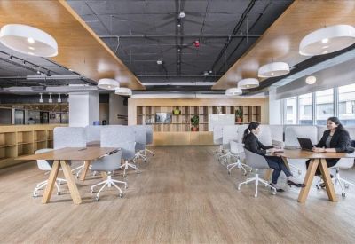 Open-plan coworking space with wooden floors and stylish round pendant lighting.