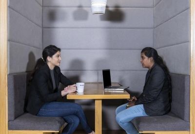A private two-person acoustic booth with grey padded walls and a central table.