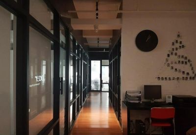 Office hallway with glass partitions, a sleek black desk, and a red chair.
