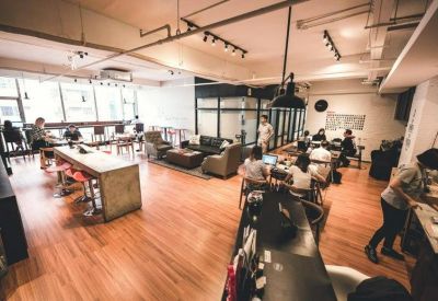 Spacious open-plan lounge area with warm wood flooring and various seating arrangements.