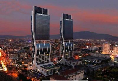 Exterior view of the modern, curved twin skyscrapers of Folkart Towers A Kule at dusk.