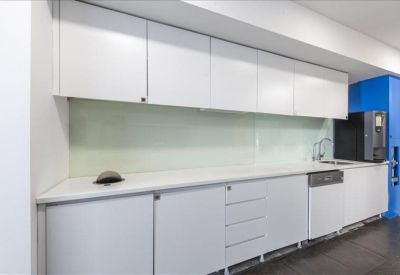 Modern white kitchen area with integrated appliances and blue accents.
