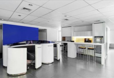 Sleek communal kitchen and breakout area with white curved seating and a breakfast bar.