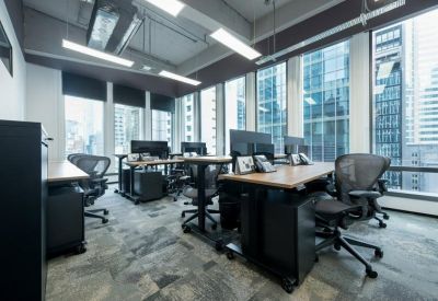 Bright open-plan office with sit-stand desks and floor-to-ceiling city views.