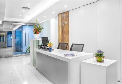 Bright white reception desk with wood-paneled feature wall and green plants.