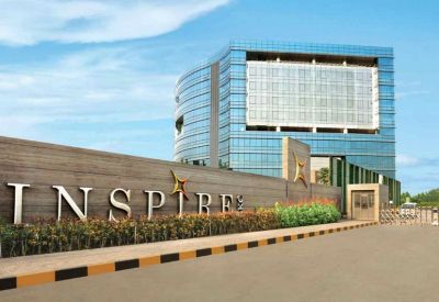 Exterior view of the modern glass facade and entrance signage of Adani Inspire.