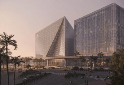 Large glass-walled office towers overlooking a palm-lined street at sunset.