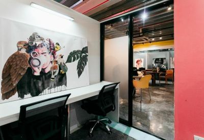 Coworking nook with a large artistic mural and white desks.