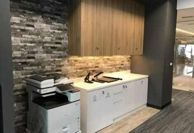 Modern print station and storage cabinets set against a textured stone wall.