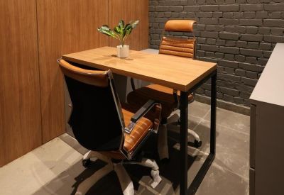 Compact private office featuring a gray brick wall and tan leather chairs.